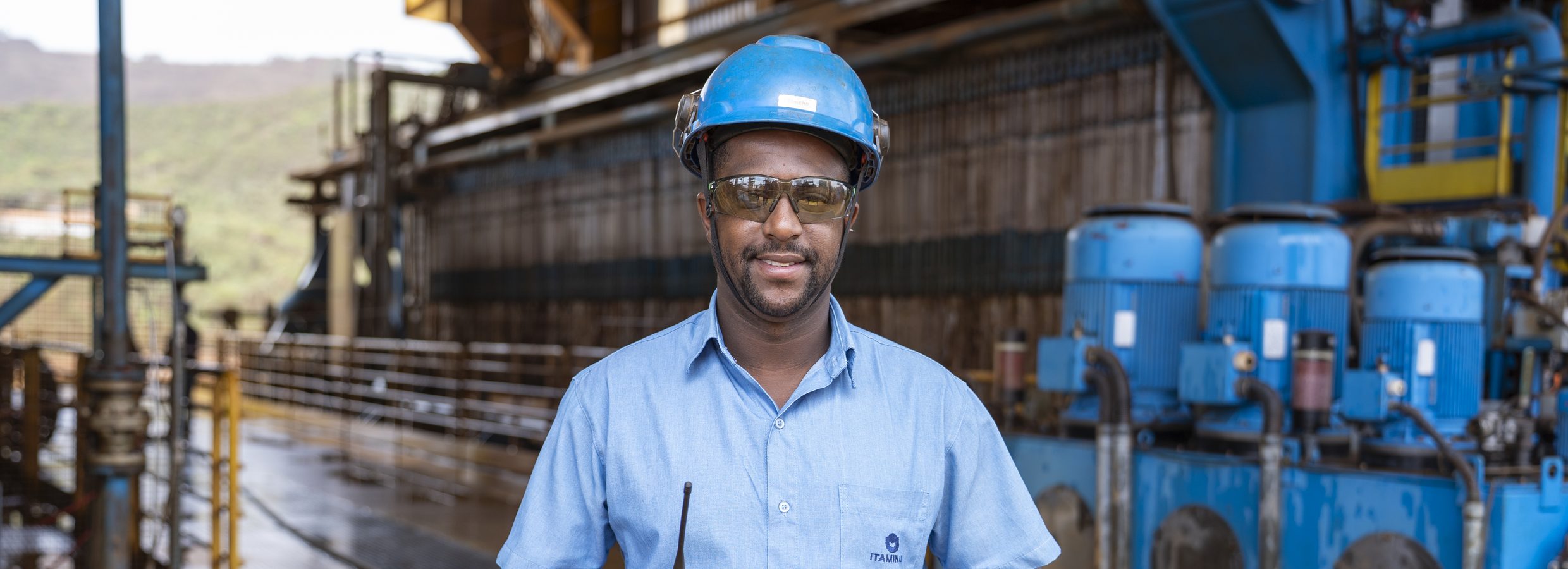 Itaminas employee wearing a hard hat and holding a radio at the industrial plant